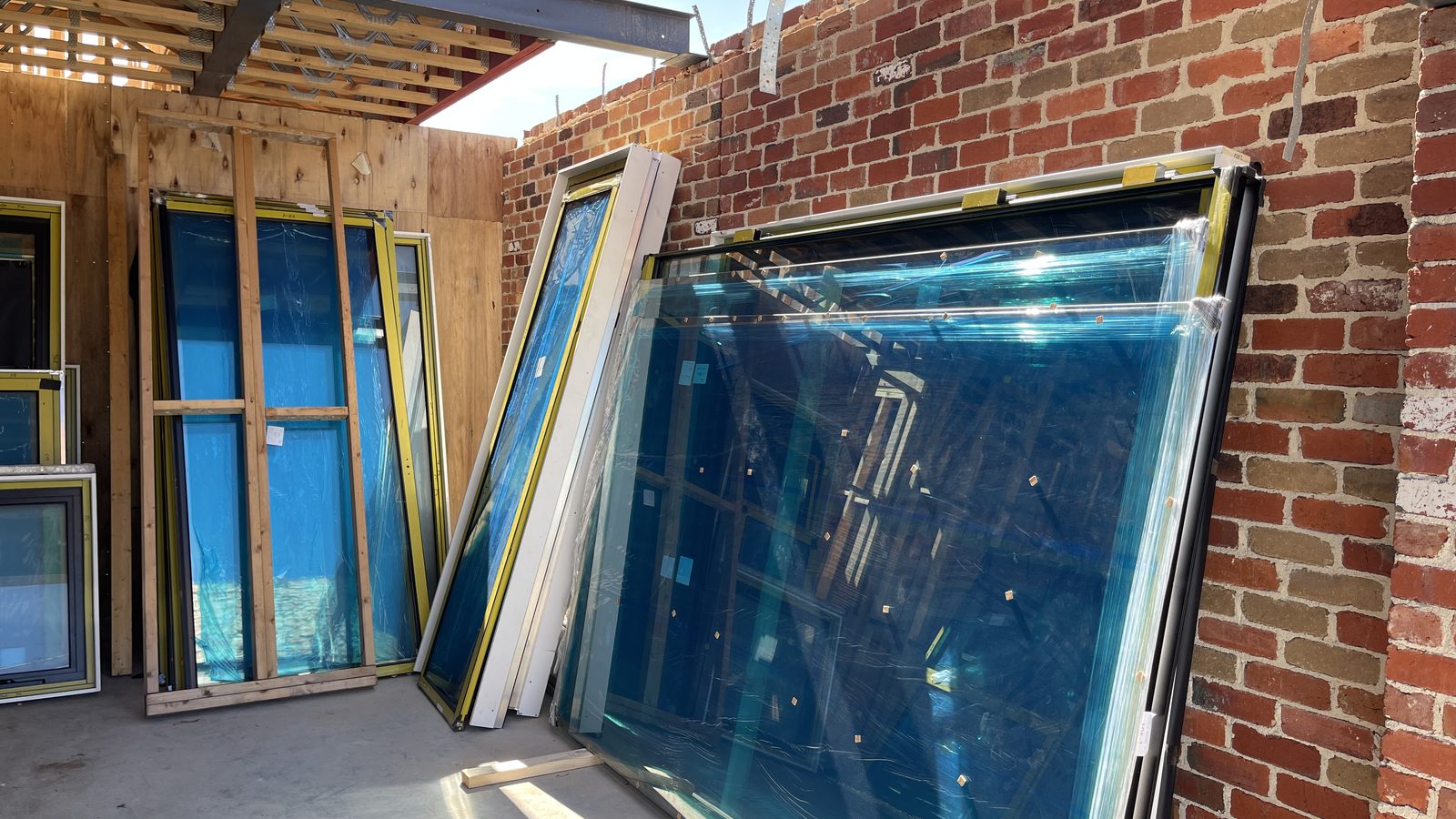 Horizontal framed glass panels staged on protective supports in a real JD Movers job, illustrating Bellfield move planning