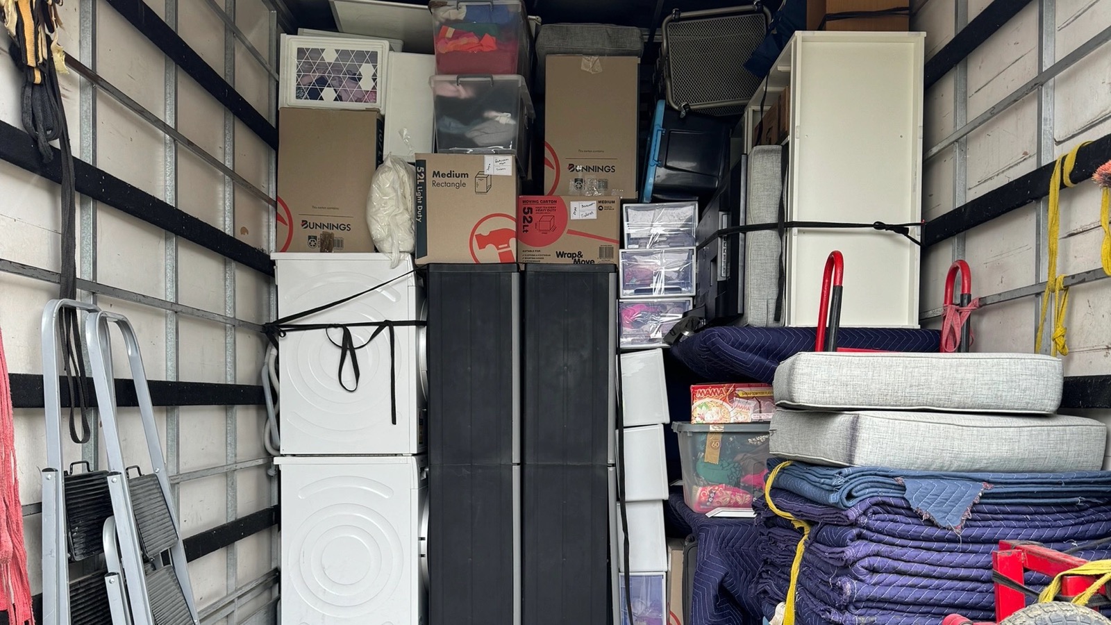 Separate real JD Movers truck load showing an upright refrigerator, cartons and protected household furniture
