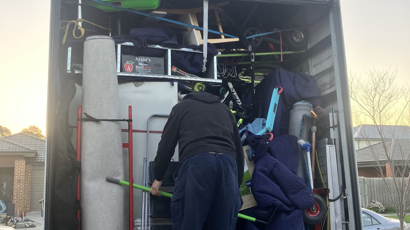JD Movers team member working beside protected furniture and moving equipment in a separate real residential job, illustrating Glen Waverley loading preparation